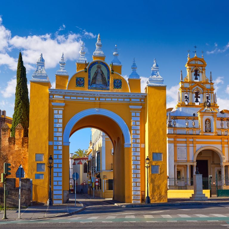 Historic yellow archway and building under a blue sky.