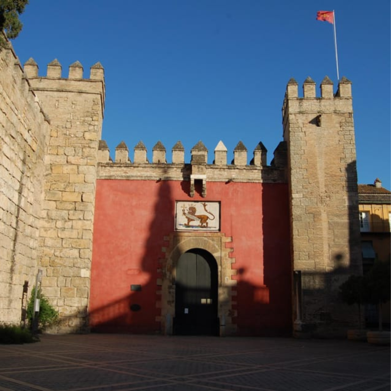 Historic castle entrance with red wall and flag, sunny day.