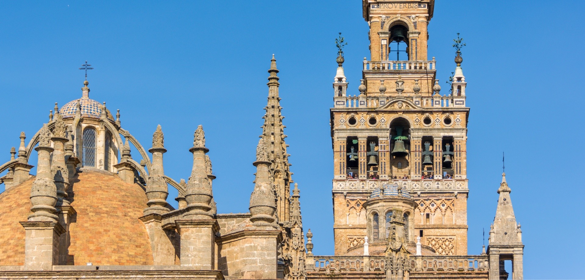 Historic cathedral with tall bell tower and spires under blue sky.