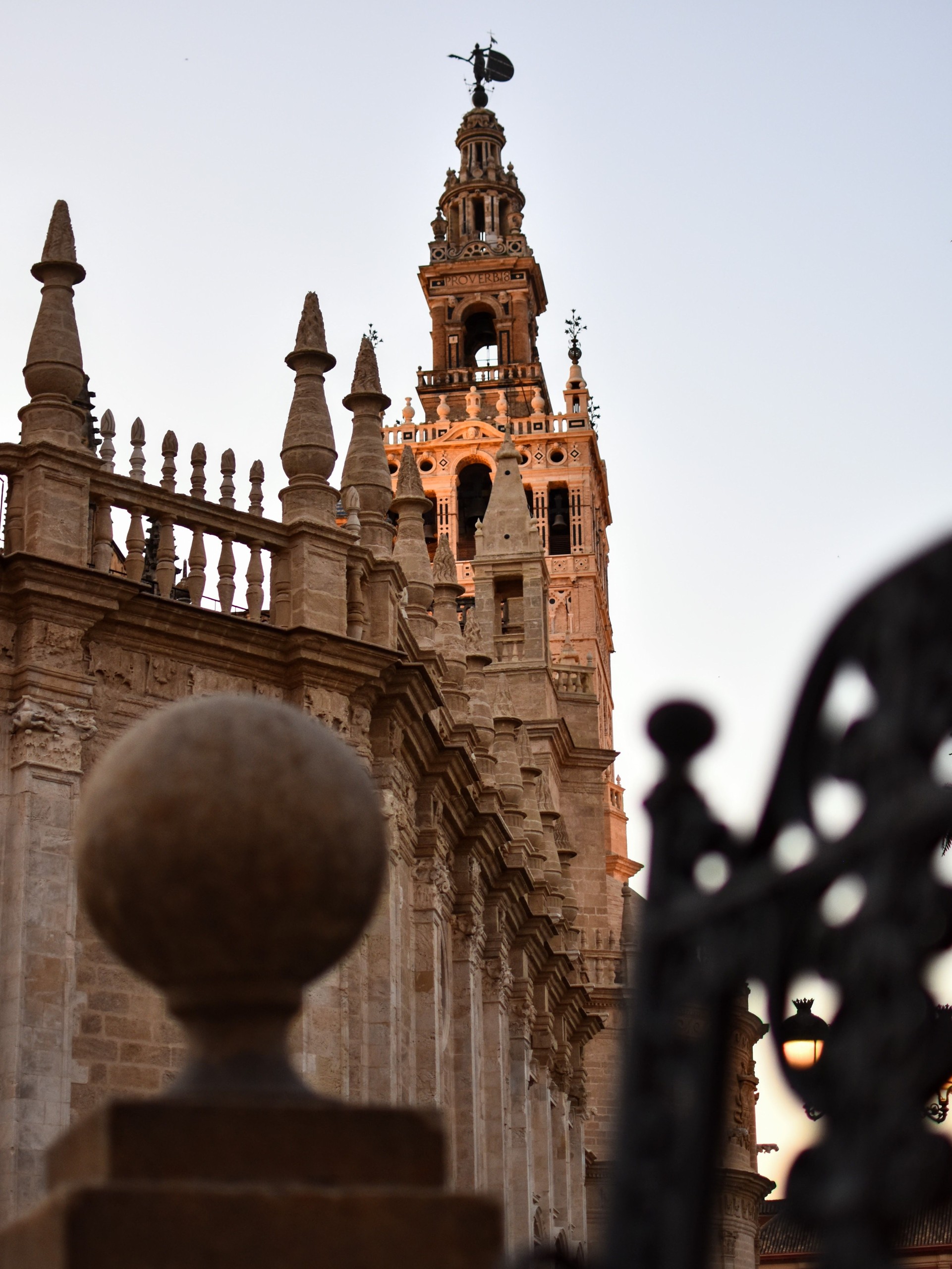 Gothic cathedral tower and ornate ironwork at sunset.