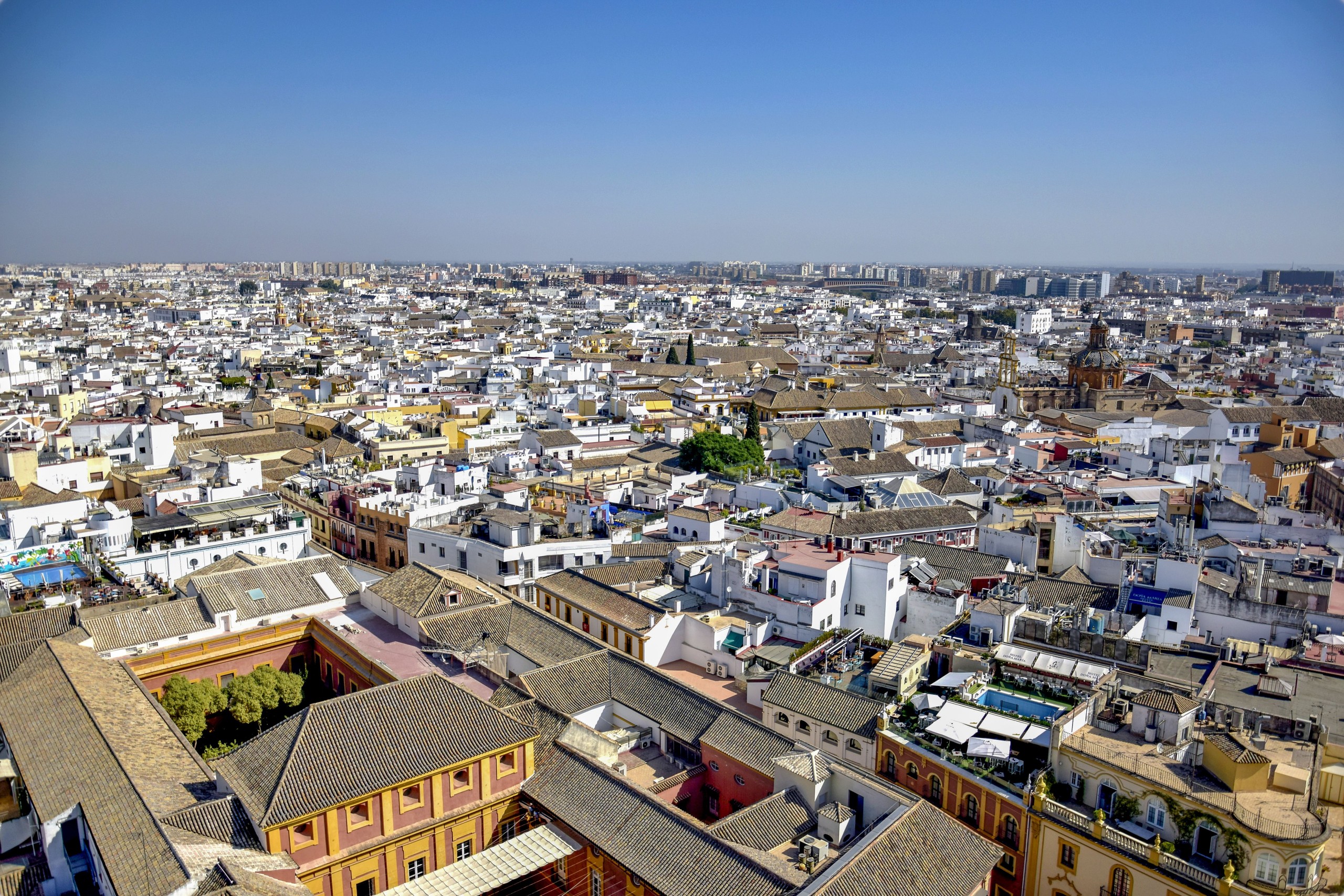 Aerial view of a sprawling cityscape with historic and modern buildings under a clear blue sky.