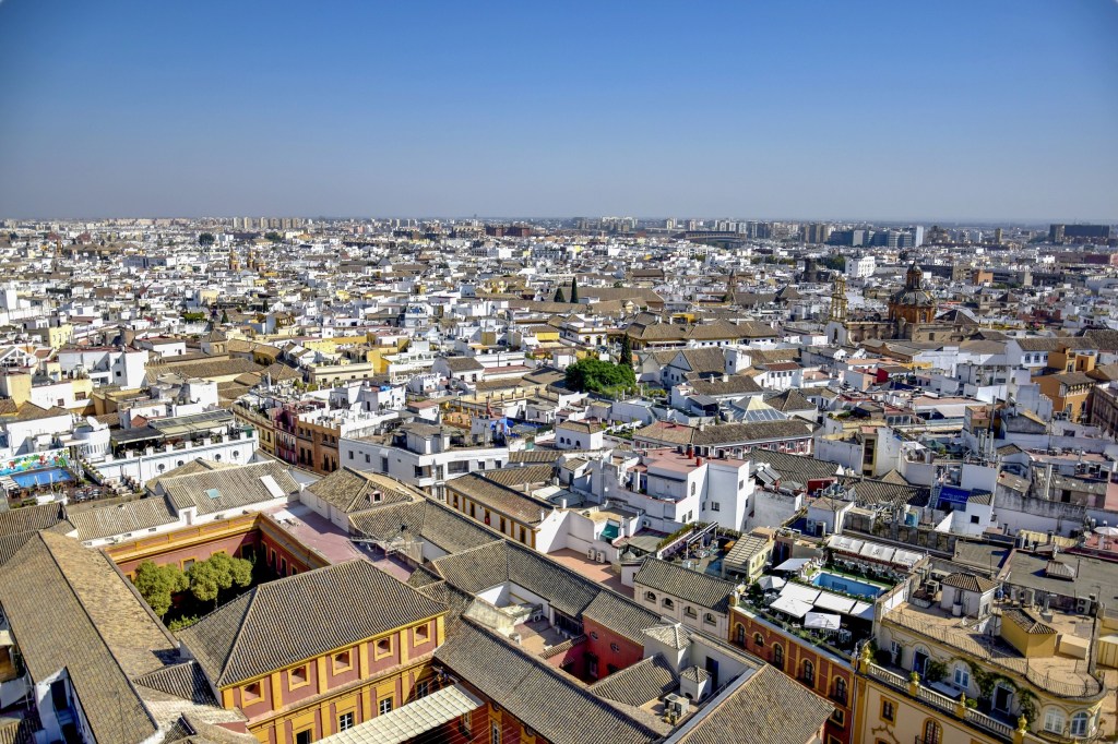 Aerial view of a sprawling cityscape with historic and modern buildings under a clear blue sky.