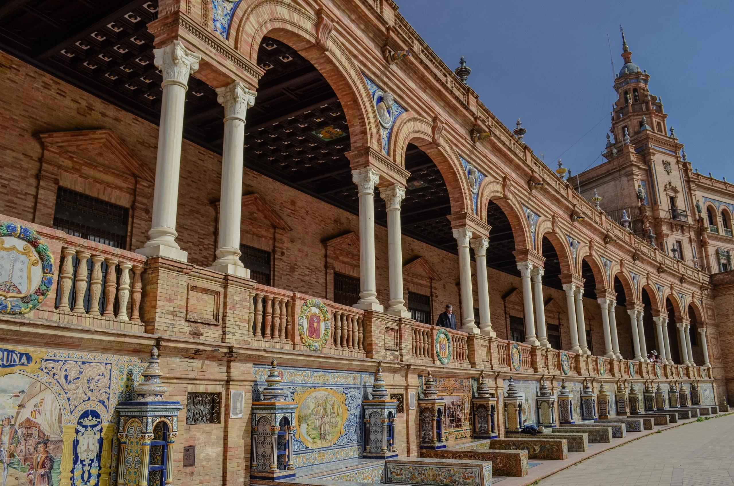 Arched colonnade with colorful tiles at Plaza de España, Seville.