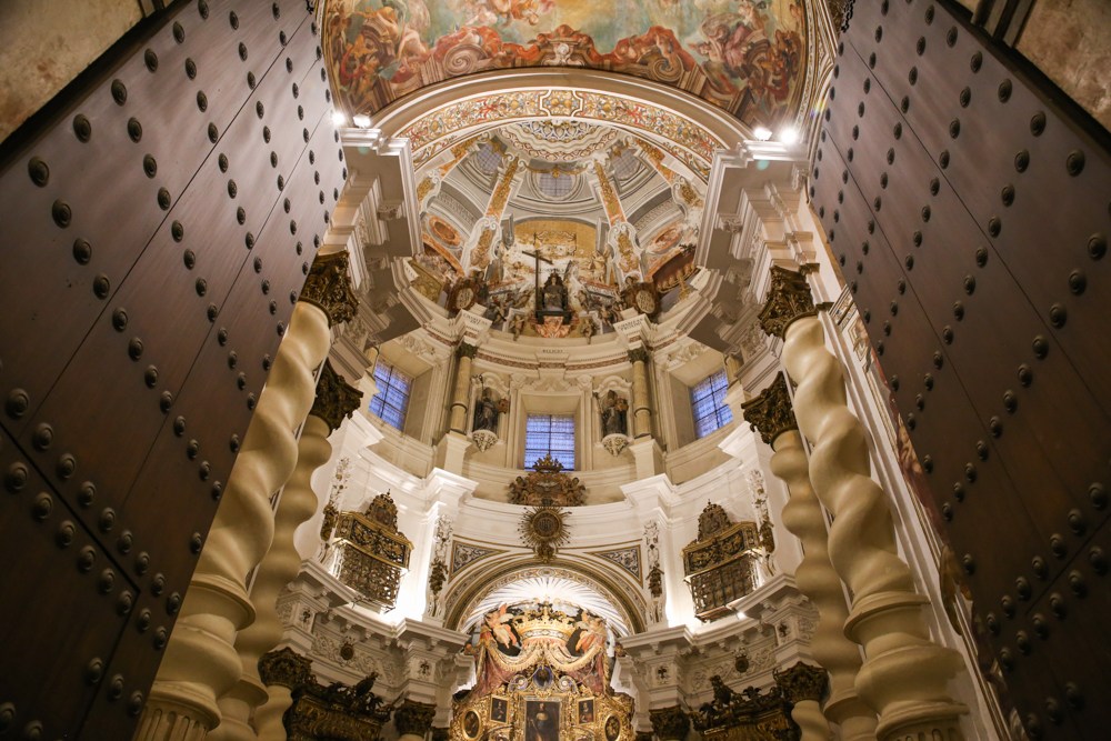 Ornate cathedral interior with tall columns and a painted dome.